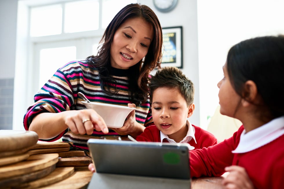 jobs for stay at home moms - Mother eating cereal looking at tablet with two children