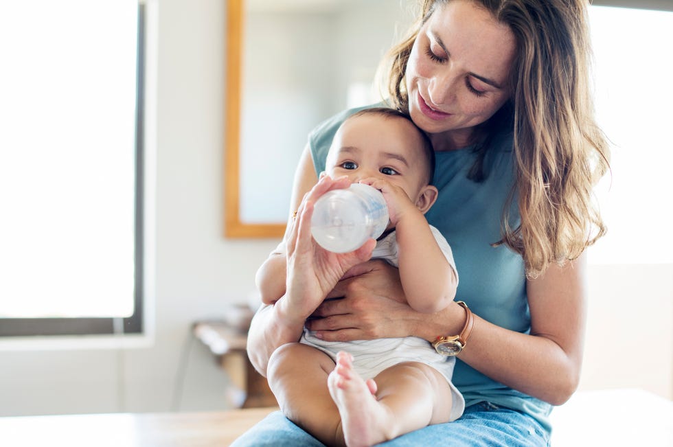 qué hacer cuando el bebé tiene fiebre ofrecerle agua como hace la madre de la foto con un biberón para que esté hidratado