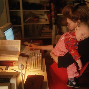 mother holding baby while working at a computer