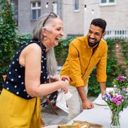happy senior woman and her son in law preparing table for dinner party in front or backyard