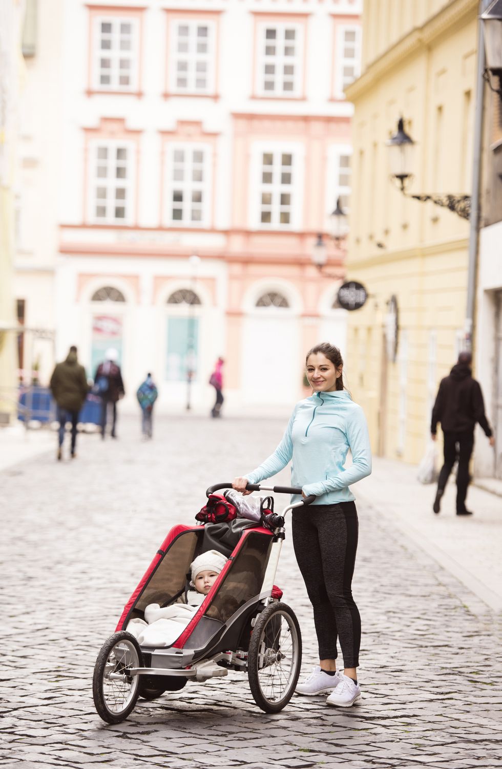 mother in sportswear with child in stroller in the city