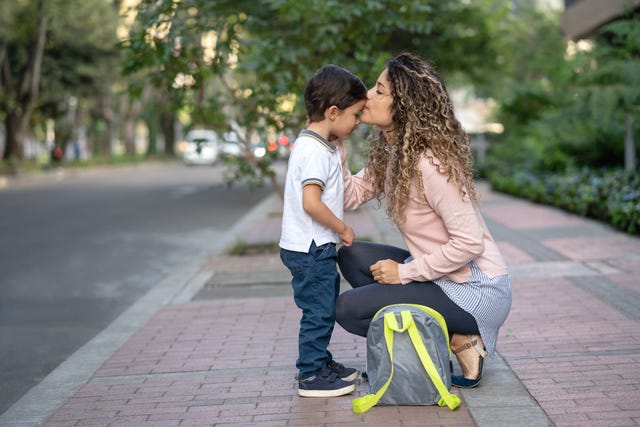 mother kissing her son goodbye while taking him to school