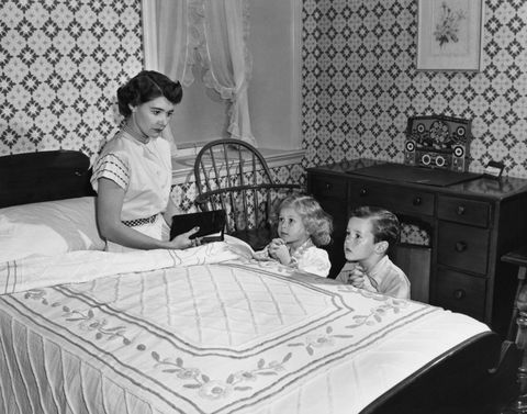 mother looking at children while they are praying bedside