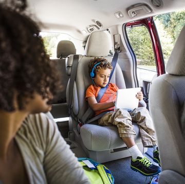 mother looking at son using laptop computer in car