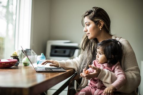 mother multi tasking with infant daughter in home office
