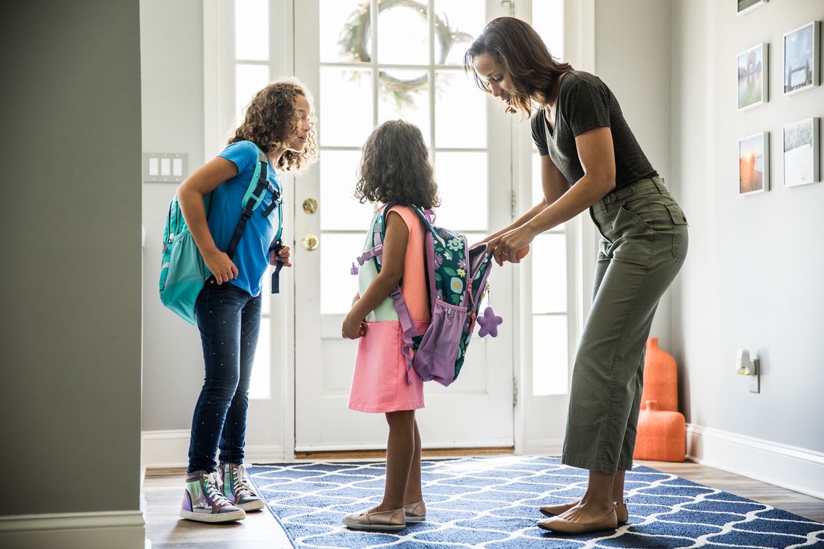 mother packing daughters backpacks for school