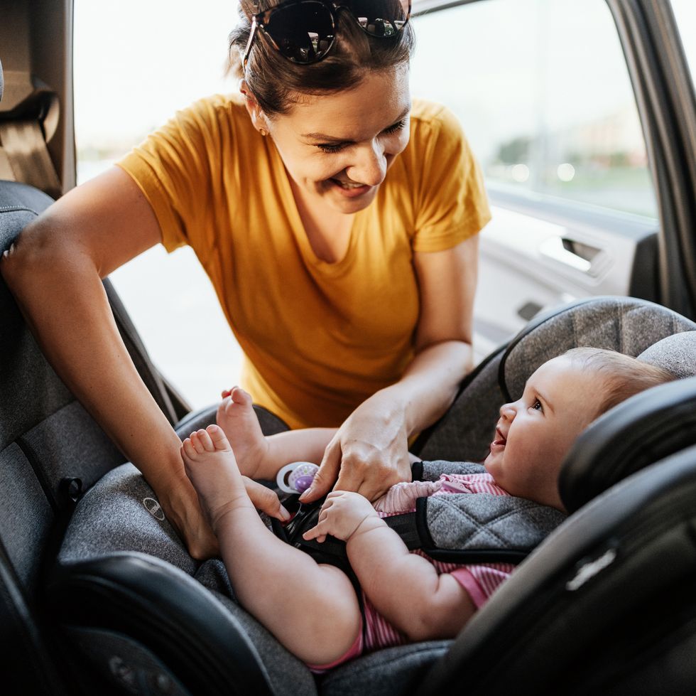 mother putting baby girl in child seat in the car