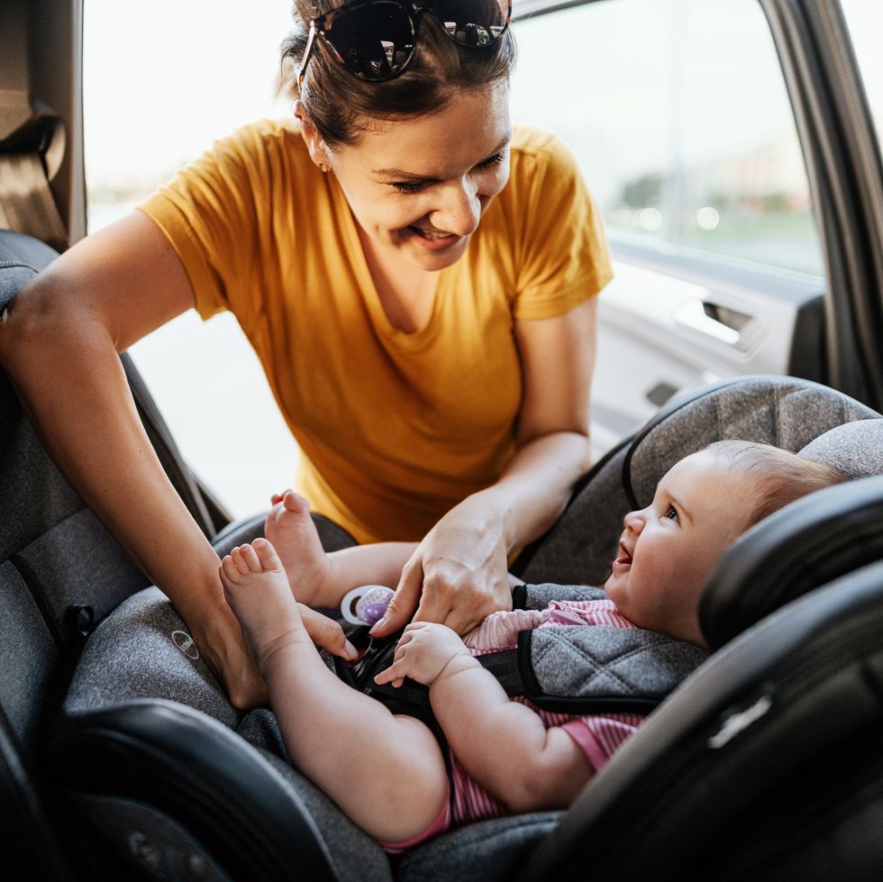 mother putting baby girl in child seat in the car