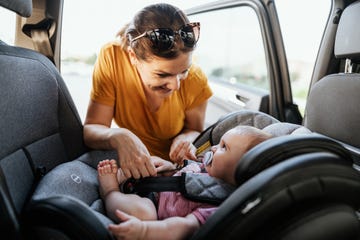 madre colocando en silla coche bebe feliz