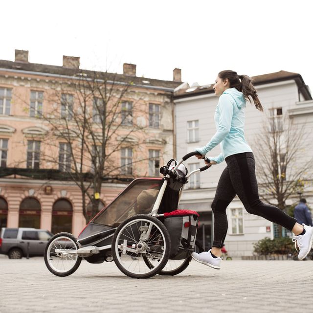 Mother running with child in stroller in the city