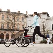 Mother running with child in stroller in the city