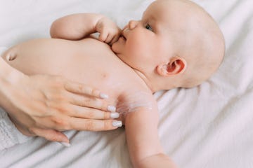 madre echando crema a bebe en el cuerpo