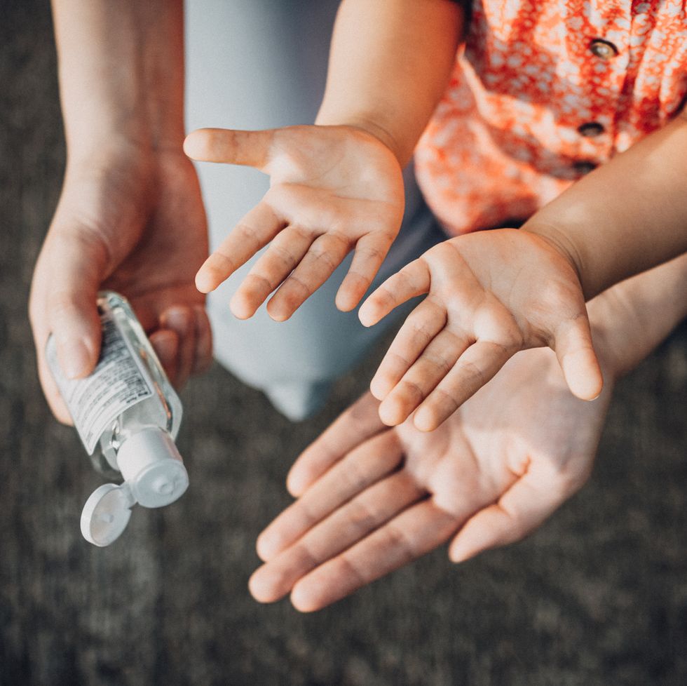 mother squeezing hand sanitizer onto little daughter's hand outdoors to prevent the spread of viruses during the covid 19 health crisis