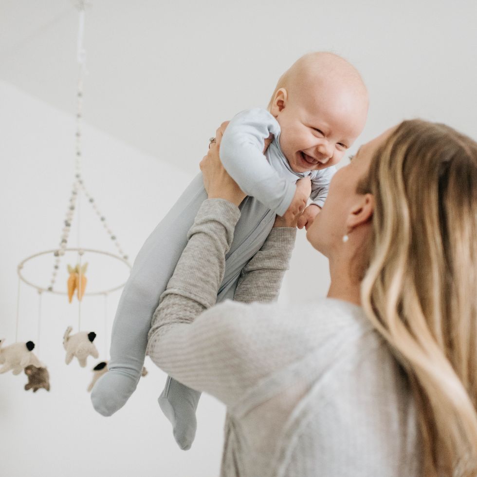 mother throwing baby boy in air in bedroom