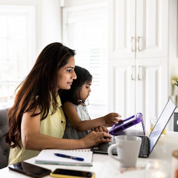 mother using laptop and smartphone while holding toddler daughter