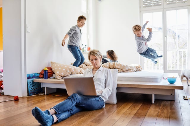 madre trabajando desde casa con sus hijos jugando