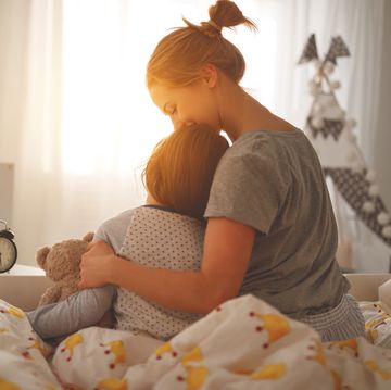 mother wakes her daughter in bed in  morning