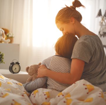 mother wakes her daughter in bed in morning