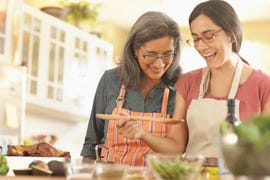 Mother watching daughter cooking in domestic kitchen