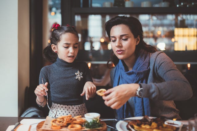 Mother with daughter eating in restaurant at dinner