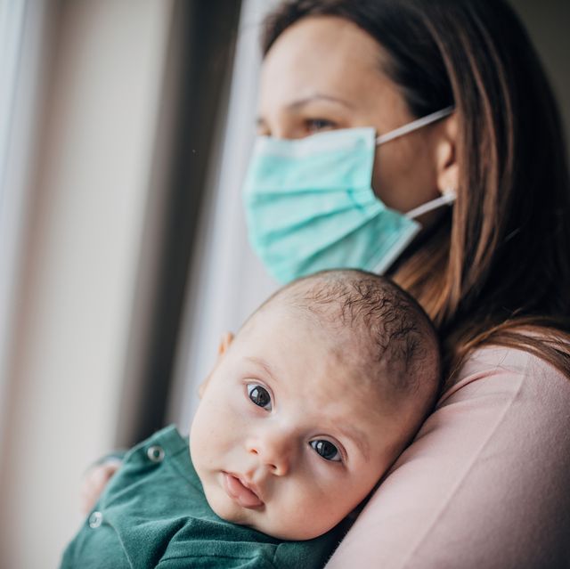 mother with protective mask holding his baby son at home do to pandemic outbreak