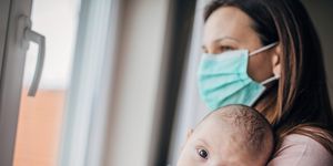 mother with protective mask holding his baby son at home do to pandemic outbreak