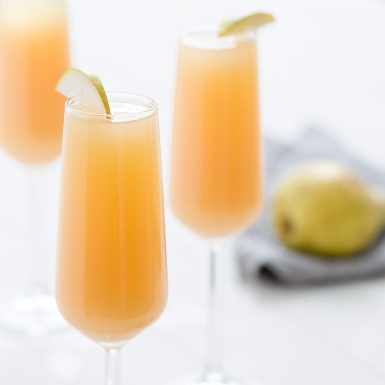 two champagne glasses filled with pear mimosas