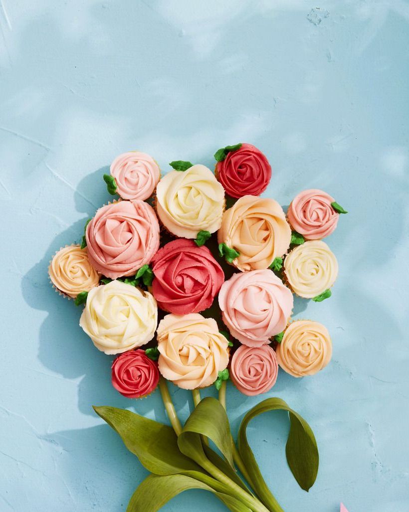 vanilla buttercream cupcakes with frosting piped like roses and arranged like a bouquet with real flower stems