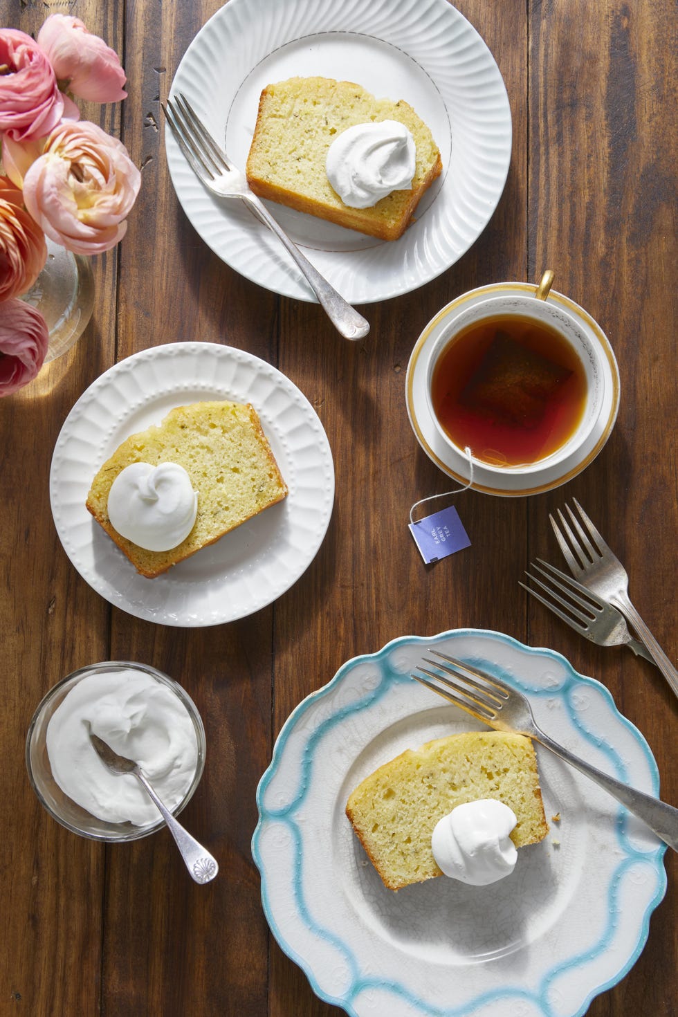 three small plates with a slice of lemon rosemary tea bread and a dollop of whipped cream on top of each