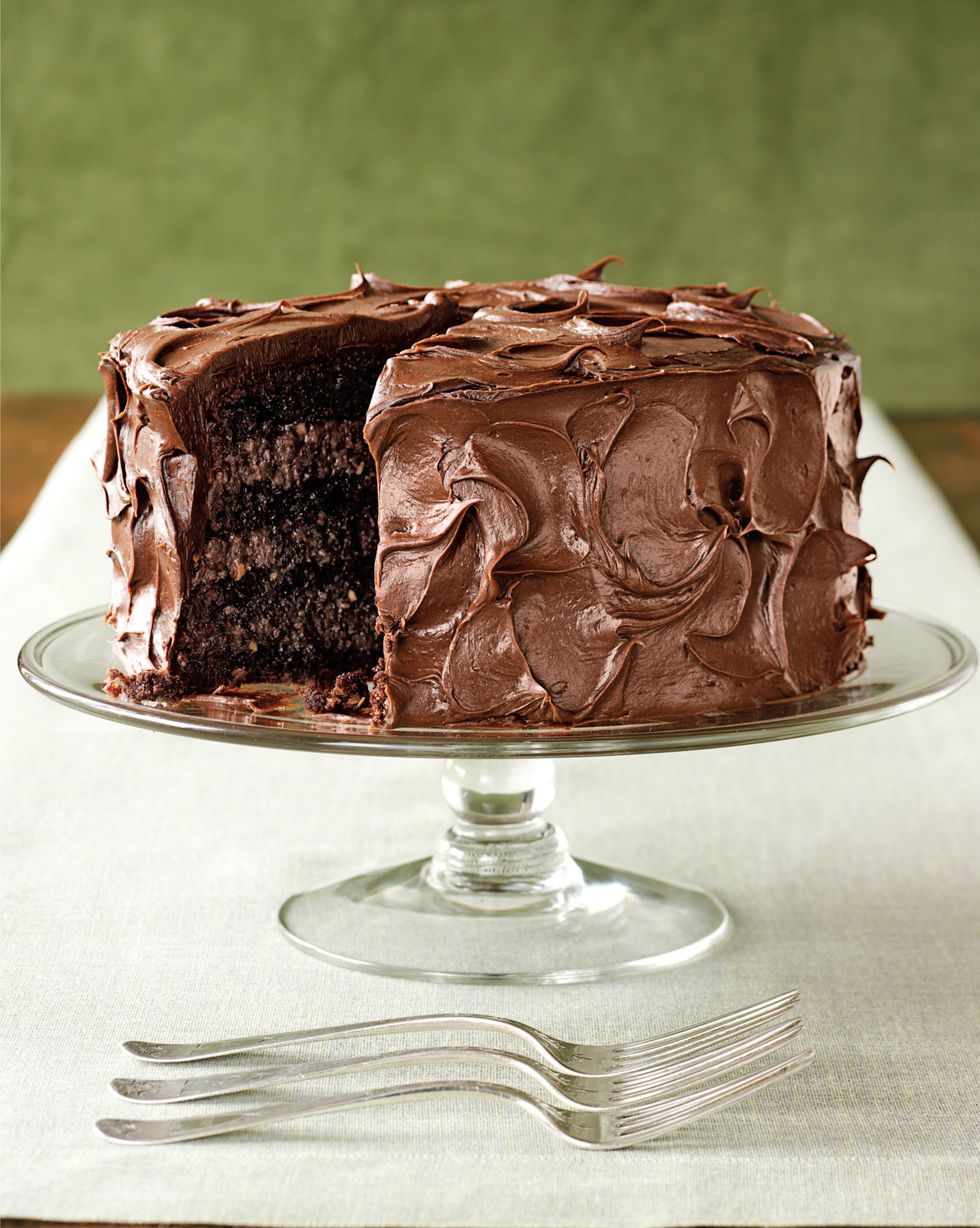 rich chocolate layer cake covered in chocolate frosting on a glass cake stand
