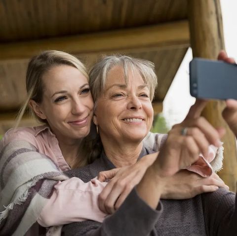 mother and adult daughter hugging and taking selfie