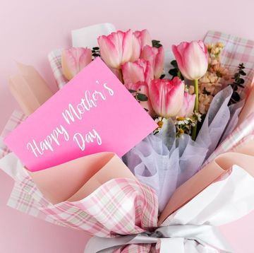 happy mother's day message on a card tucked into a tulip bouquet wrapped in pastel and plaid tissue paper