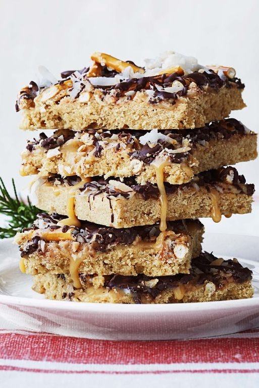 candy bar cookies stacked on top with pretzels, toffee bits, and toasted coconuts on top