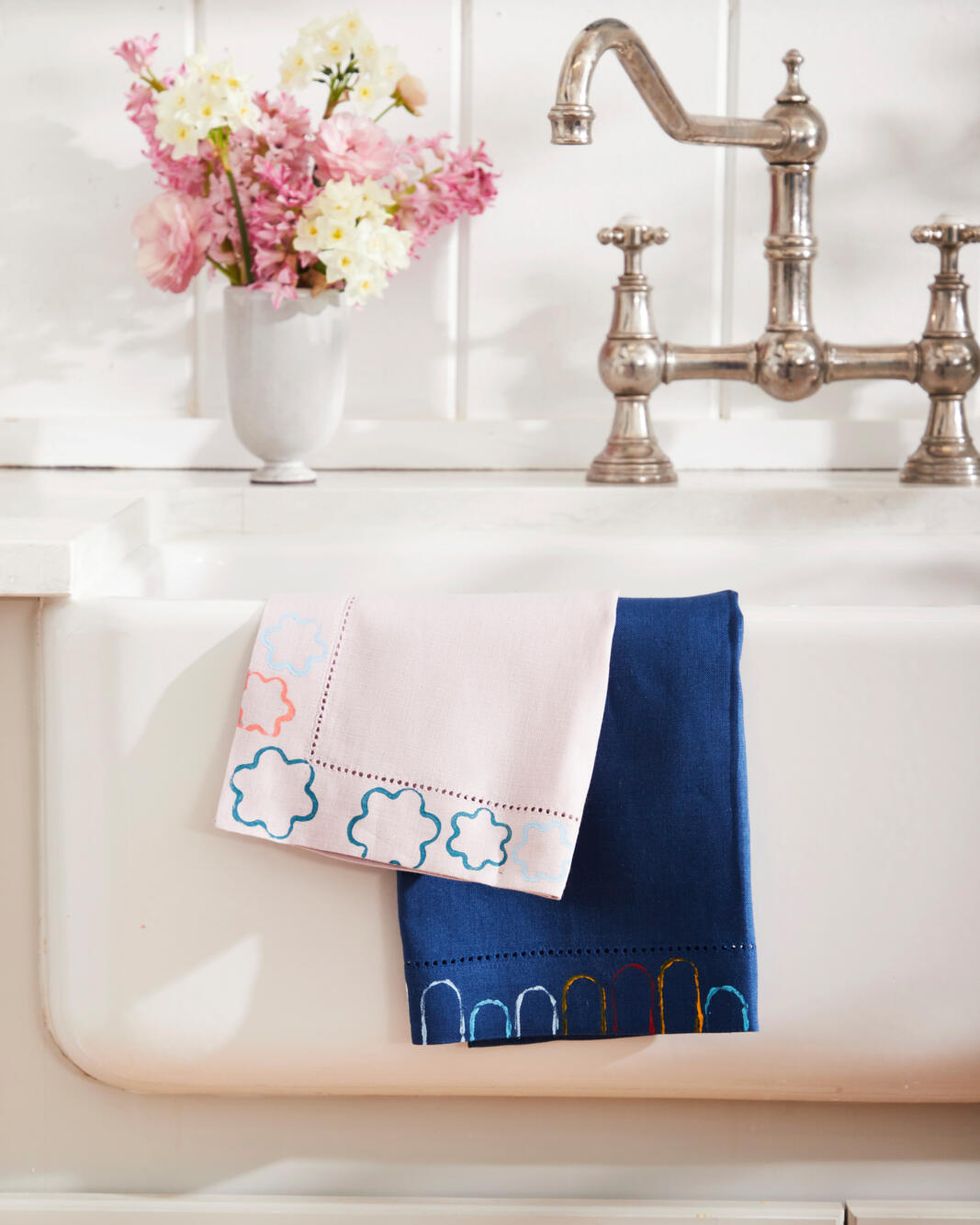 A printed dish towel hung over the farm sink and a bouquet of pink flowers sat on the counter.