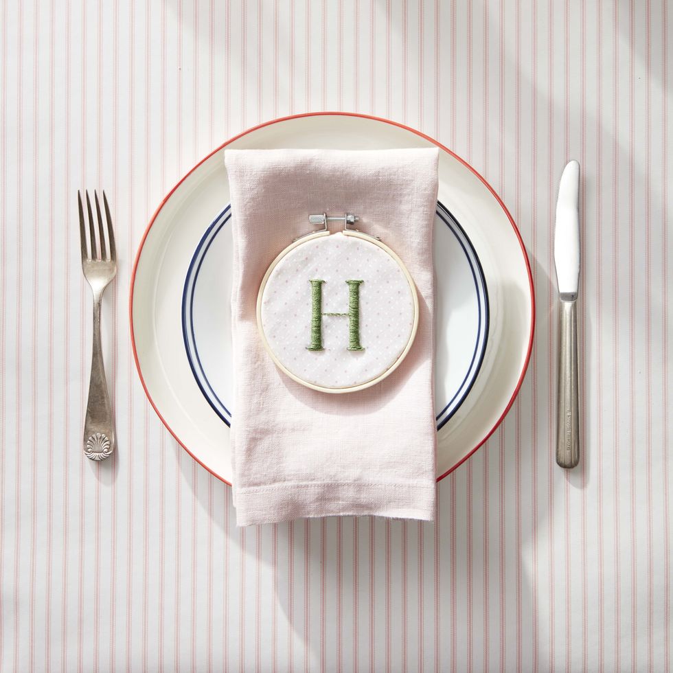 an embroidered capital h framed by a small hoop adorns a simple place setting