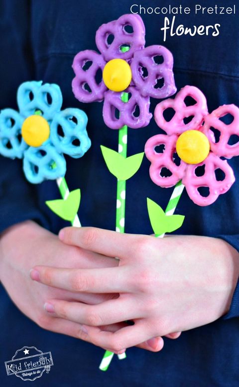mothers day crafts for kids, hand holding colorful chocolate pretzel flowers