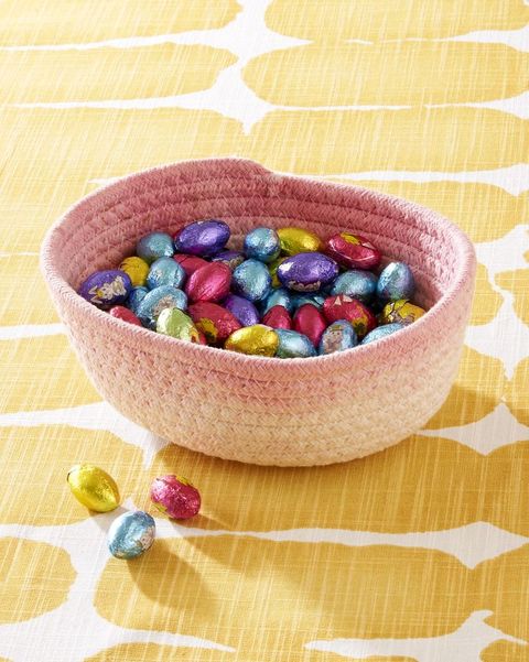 pink dip dyed cotton rope basket filled with chocolate eggs on a yellow and white tablecloth