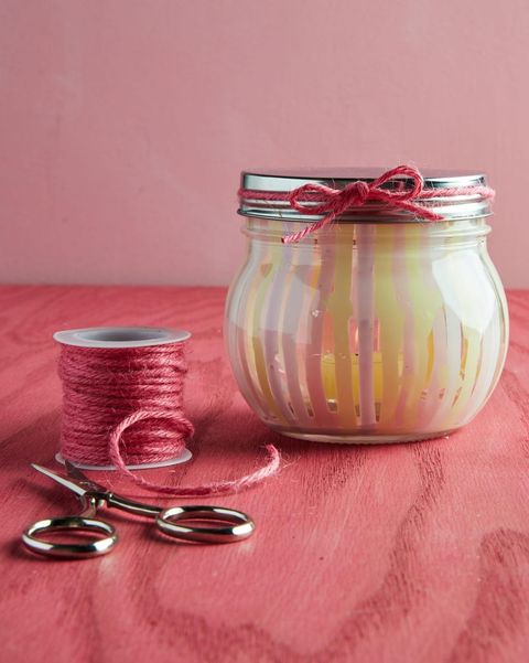 short mason jar with pale yellow and pink vertical stripes painted on the inside holding a battery powered votive candle