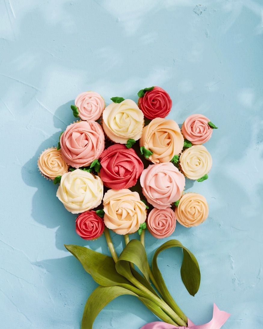 vanilla cream cupcakes with frosting piped to look like roses and cupcakes arranged in the shape of a bouquet with real flower stems next to them