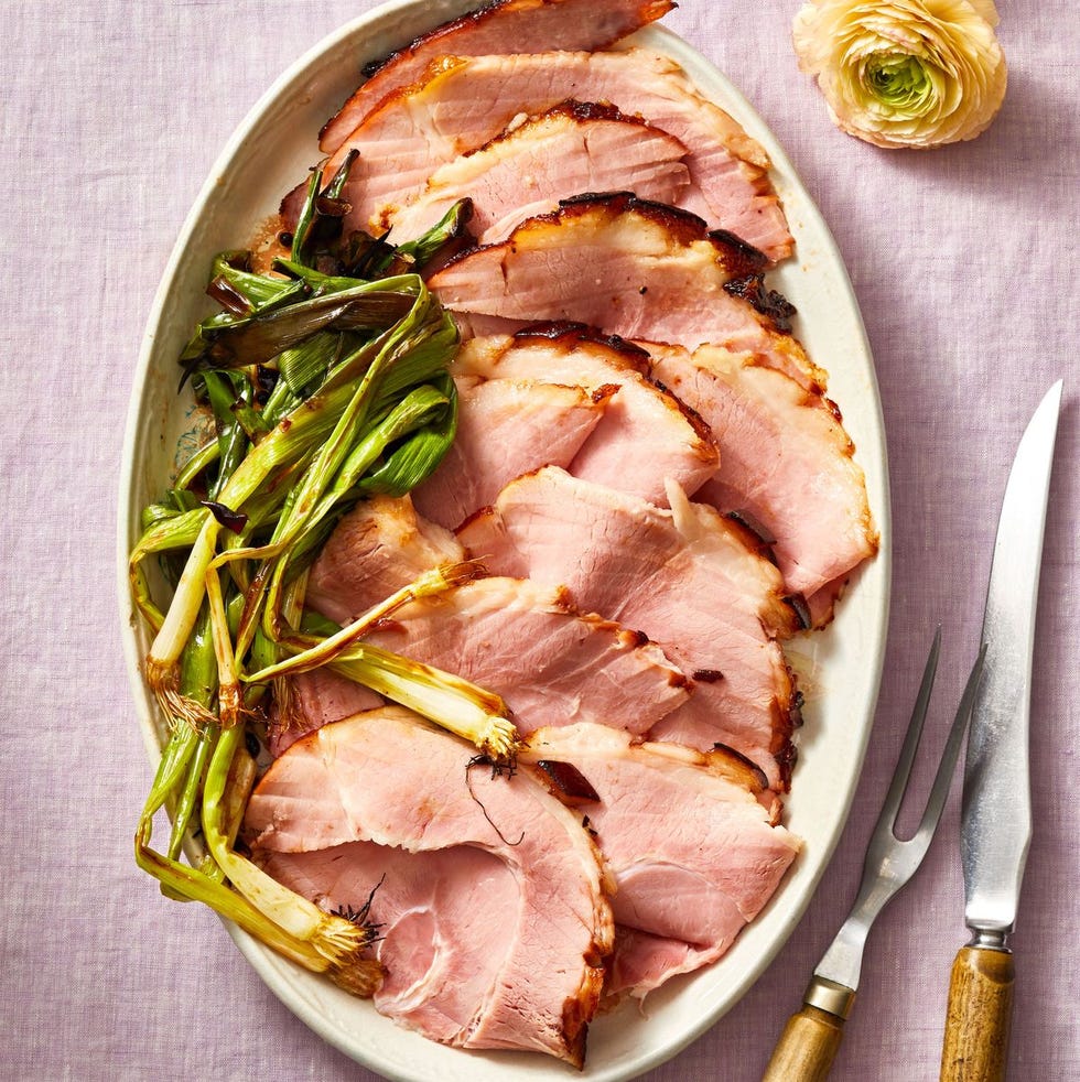sliced bourbon glazed ham with charred scallions on the side