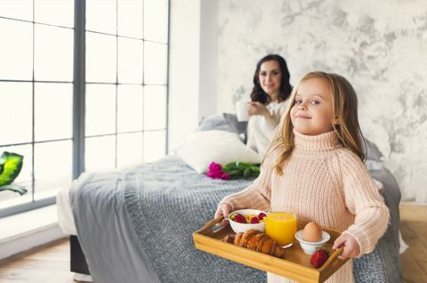 daughter with breakfast for mother in bedroom