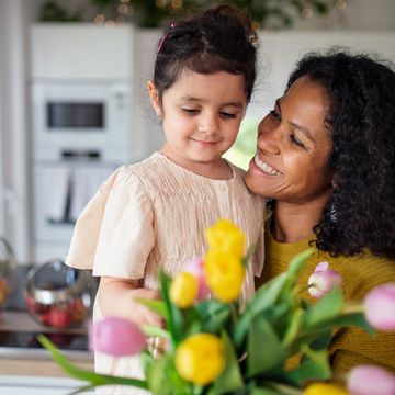girl giving flowers to her mother in their kitchen