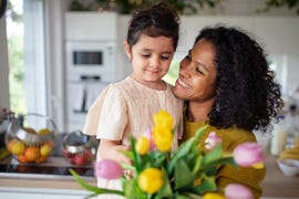 girl giving flowers to her mother in their kitchen