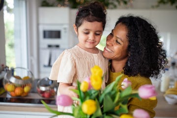 girl giving flowers to her mother in their kitchen