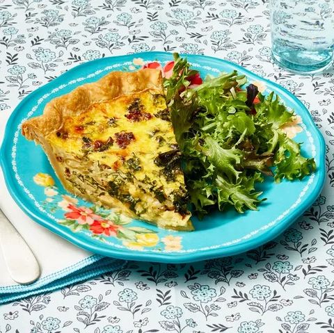 sausage and kale quiche on blue plate with side salad