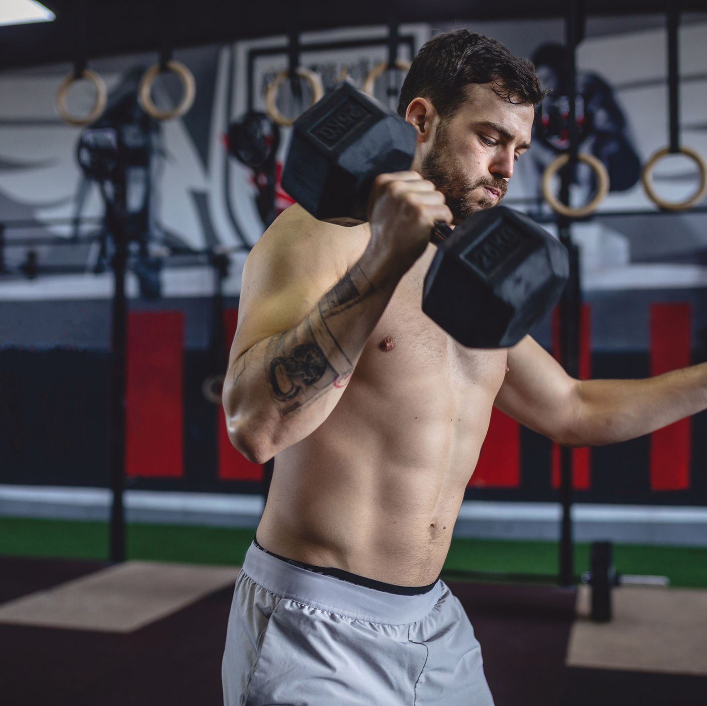 Motivated athlete exercising with dumbbells at a gym