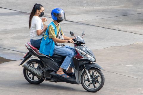 a taxi driver on a motorcycle rides with a woman