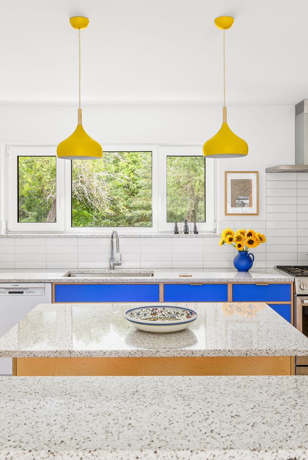 blue kitchen cabinets with yellow pendants
