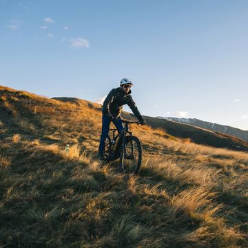 mountain biker traverses ridge crest above mountains