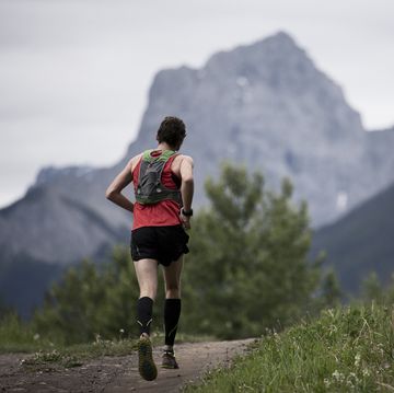 man aan het hardlopen in de bergen met een hardlooprugzak op zijn rug